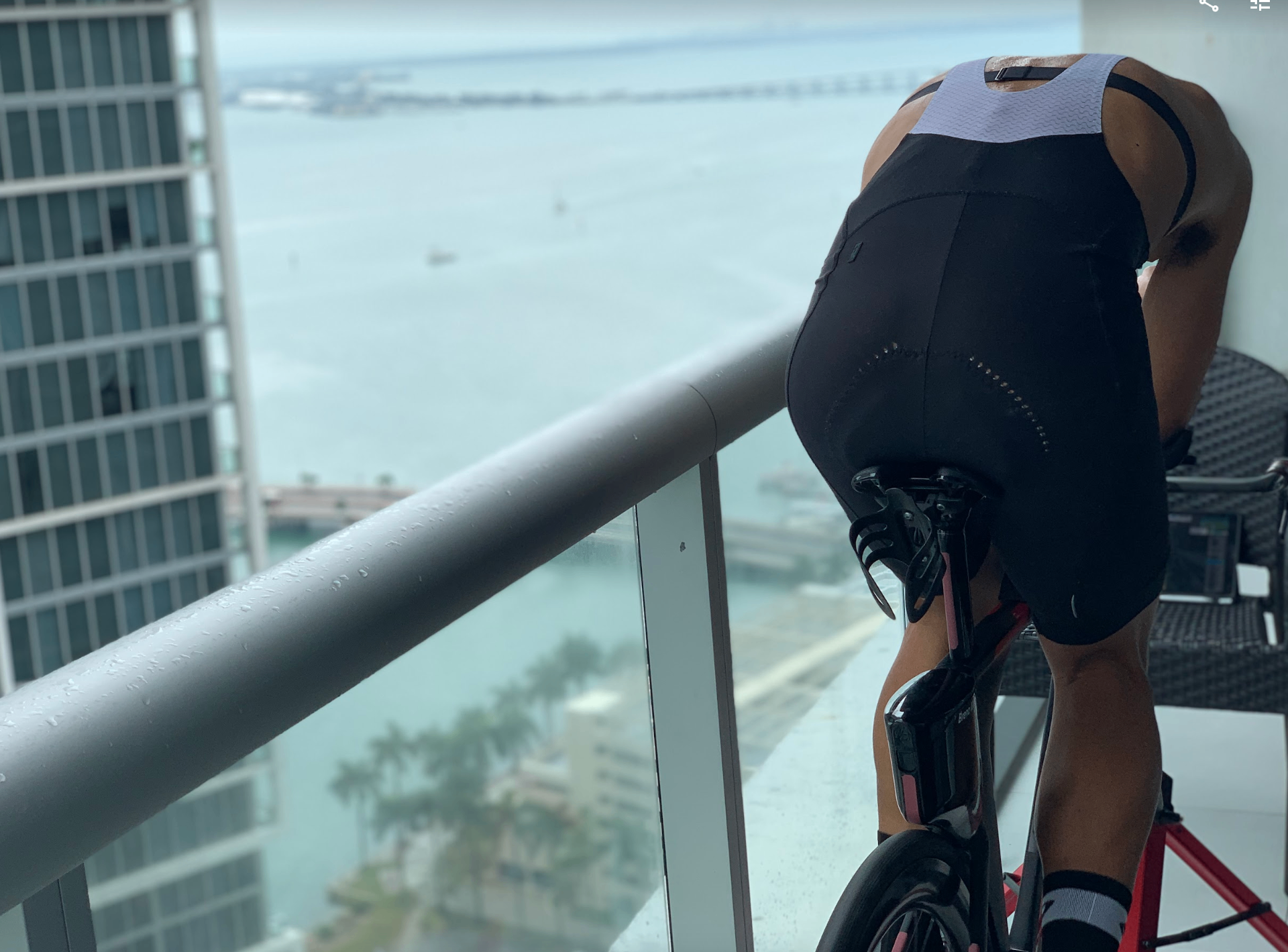 Breno Melo riding the indoor trainer in aero position on a Miami Brickell balcony overlooking Biscayne Bay