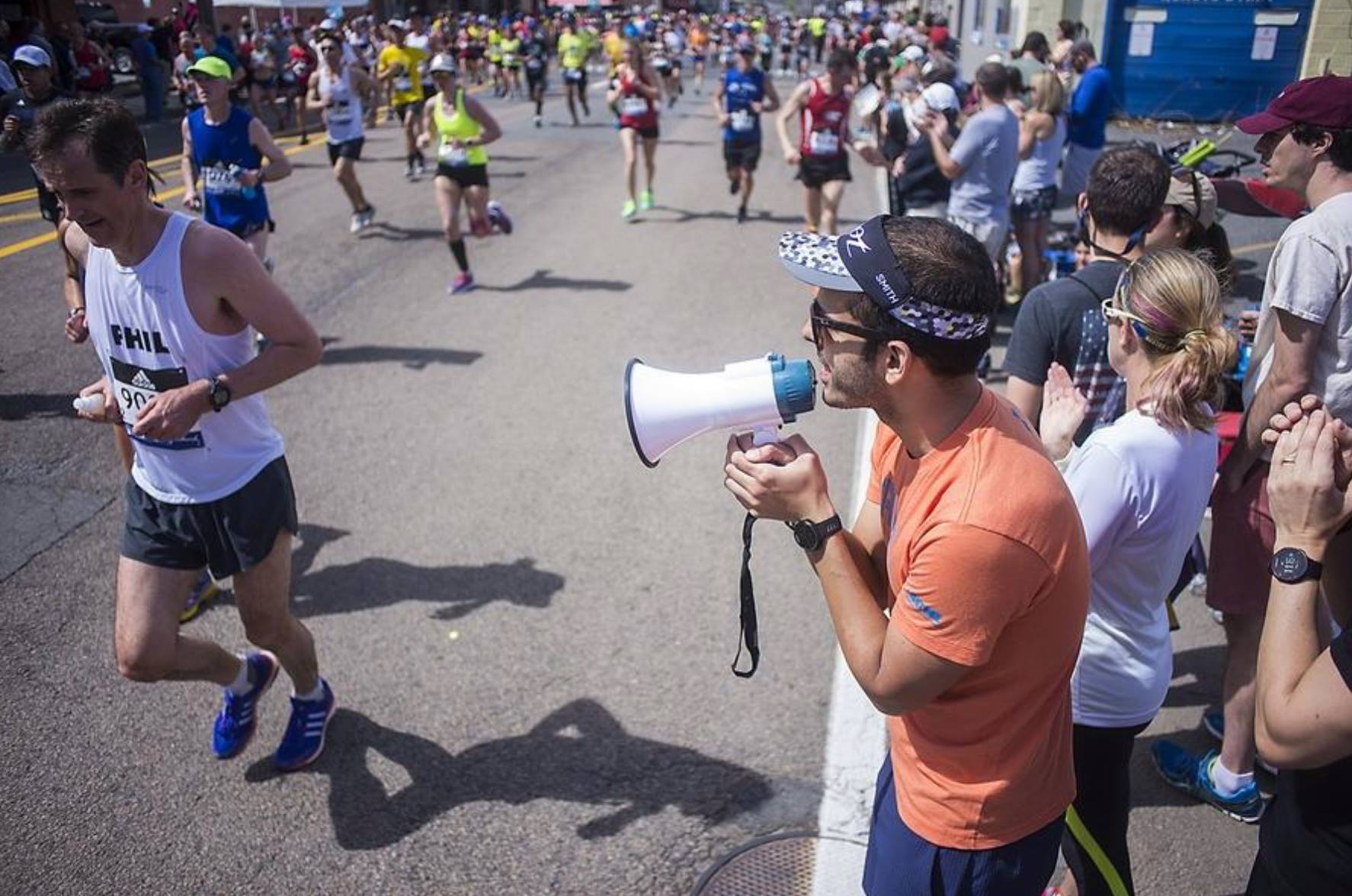 Breno Melo coaching athletes on the Boston Marathon course with a megaphone