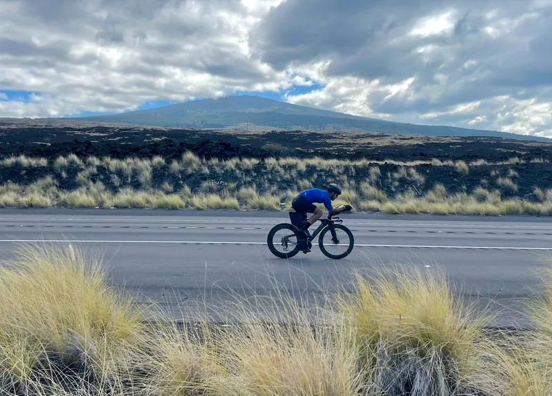 Breno rides on a road through open mountain terrain beneath a cloudy sky